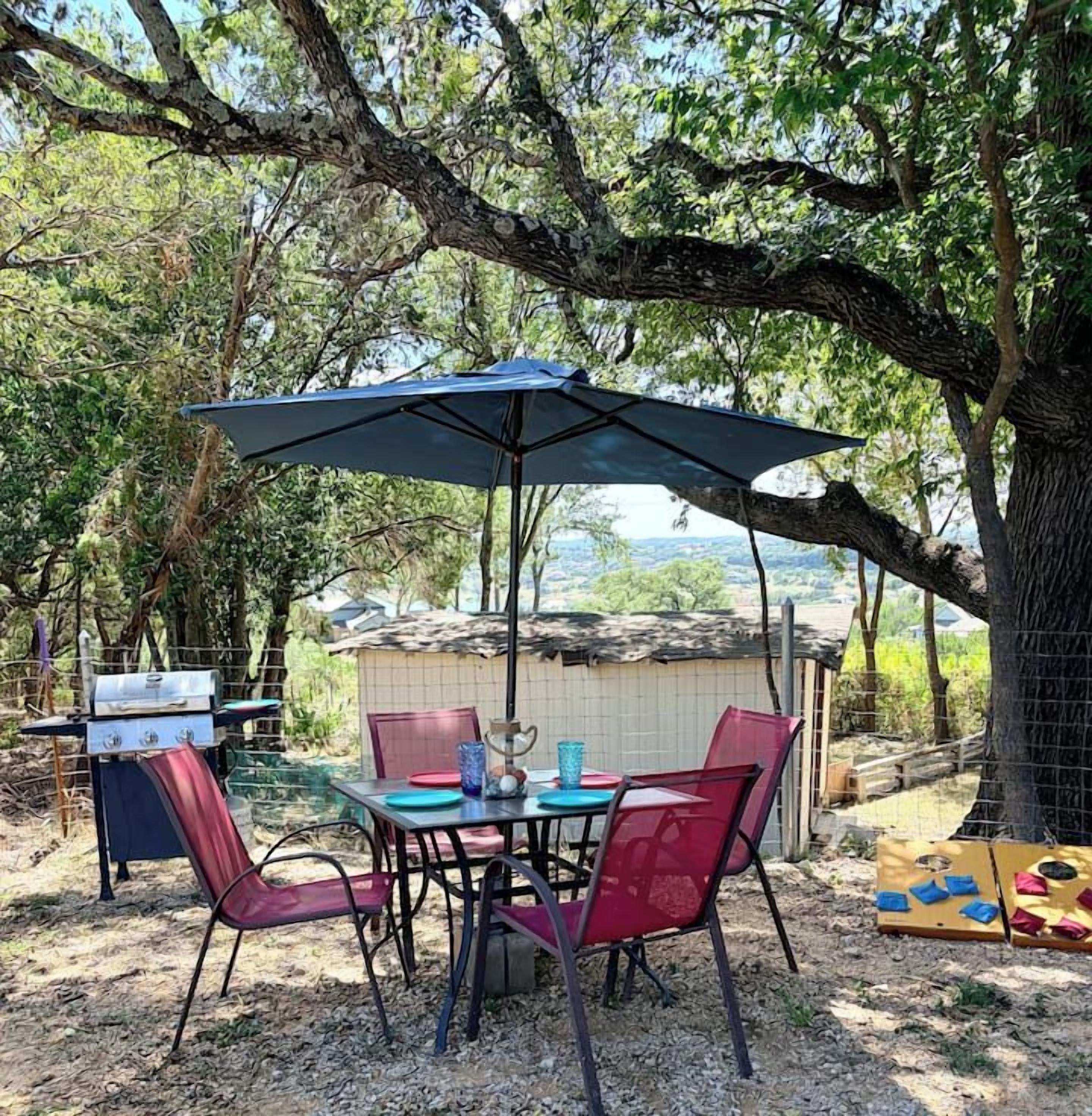 An outdoor dining area with a table, chairs, and a grill.