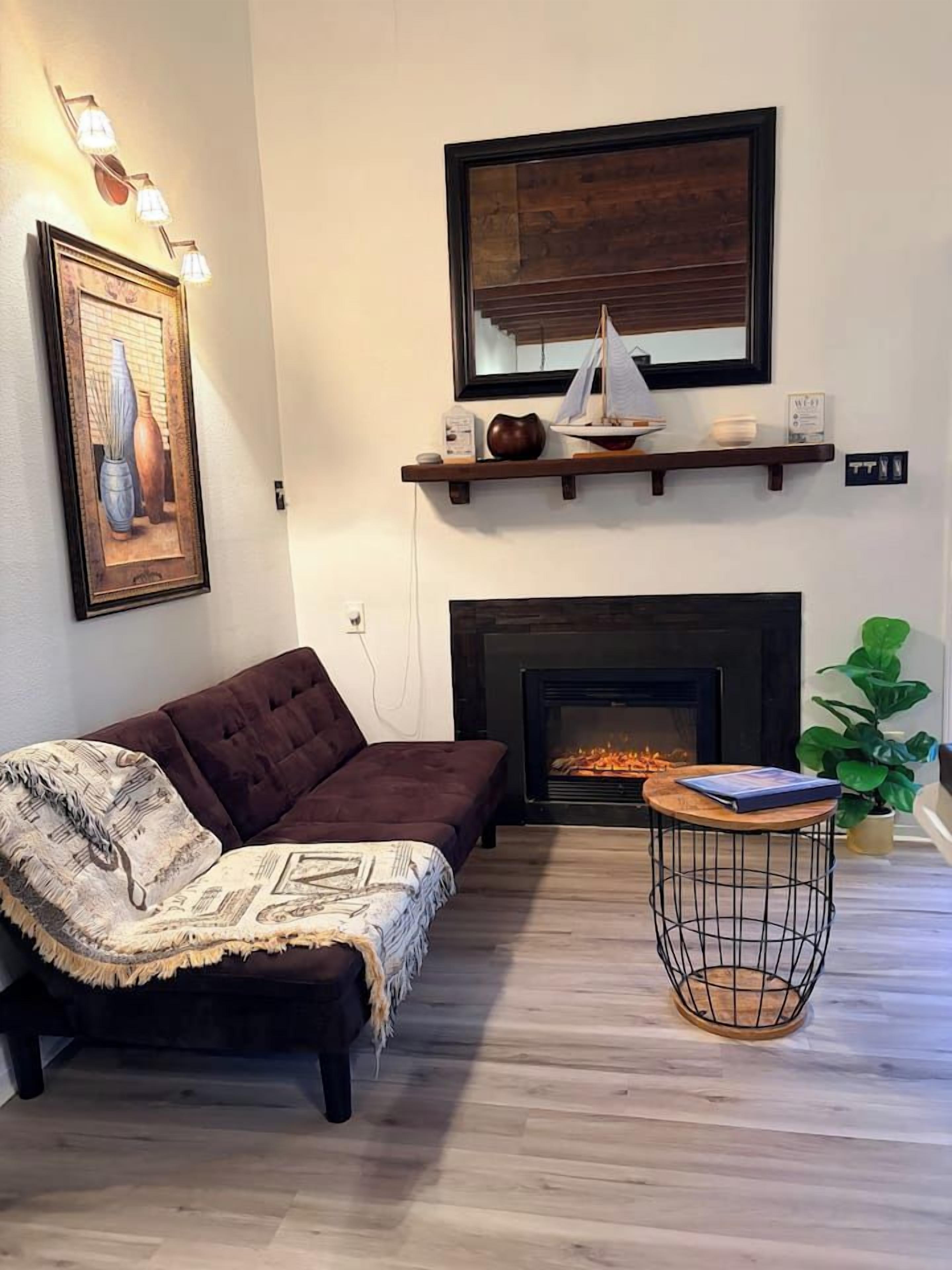 A living room with a fireplace, a sofa, a coffee table, and a plant.