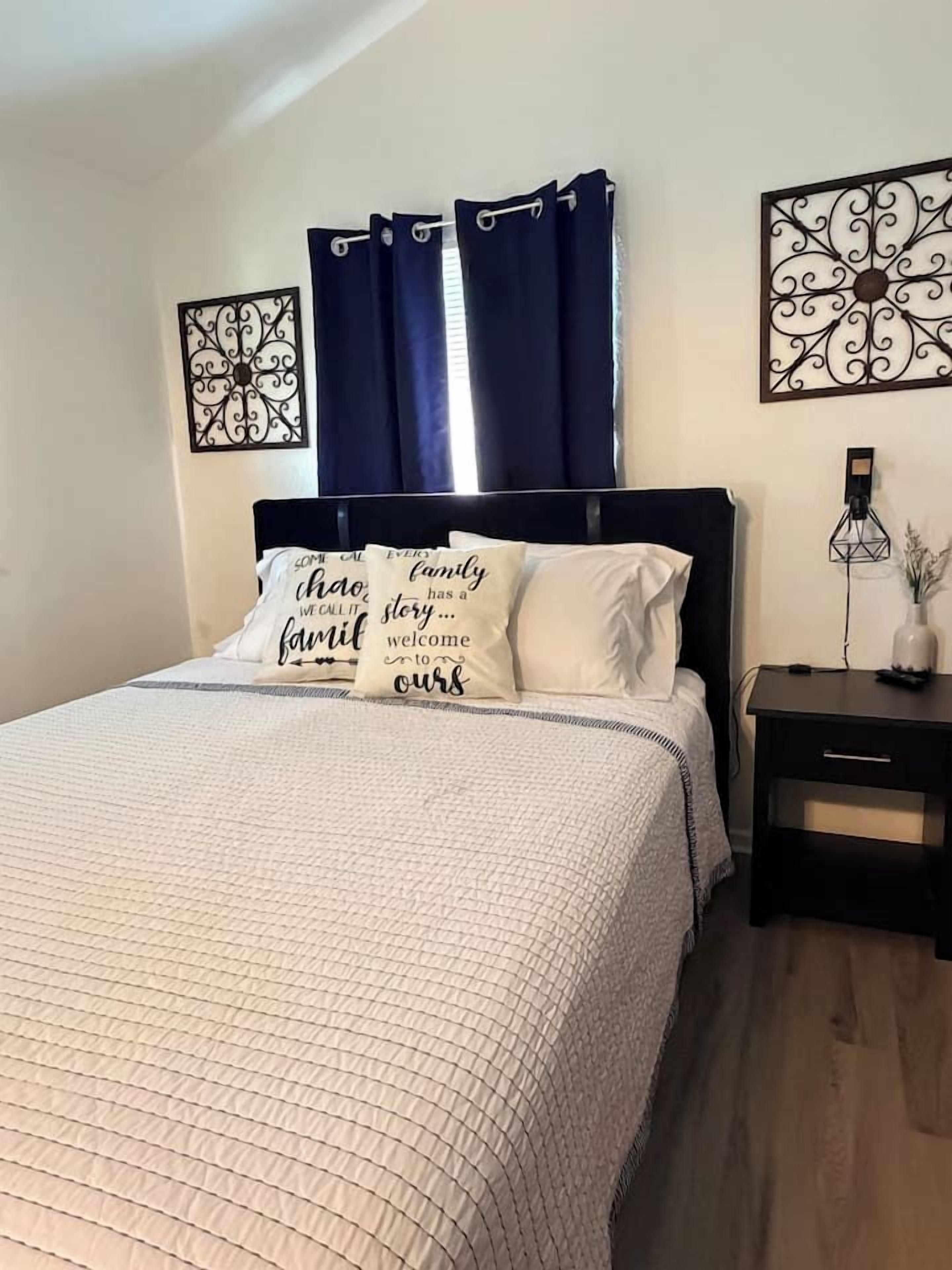 A bedroom with a bed, a nightstand, and decorative wall art.