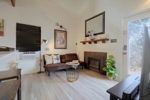 A living room with a brown sofa, a fireplace, a television, and a plant. - Private Casita - Hot Tub, Loft, Near Boat Ramp 23 (Canyon Lake)