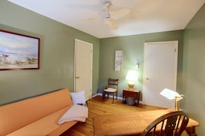 A room with a ceiling fan, a painting on the wall, a door, a chair, a table with a lamp, and a couch. - Small Town Charm: Historic Eastover Home (Eastover)