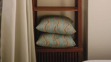 A wooden shelf unit with folded towels and patterned pillows.