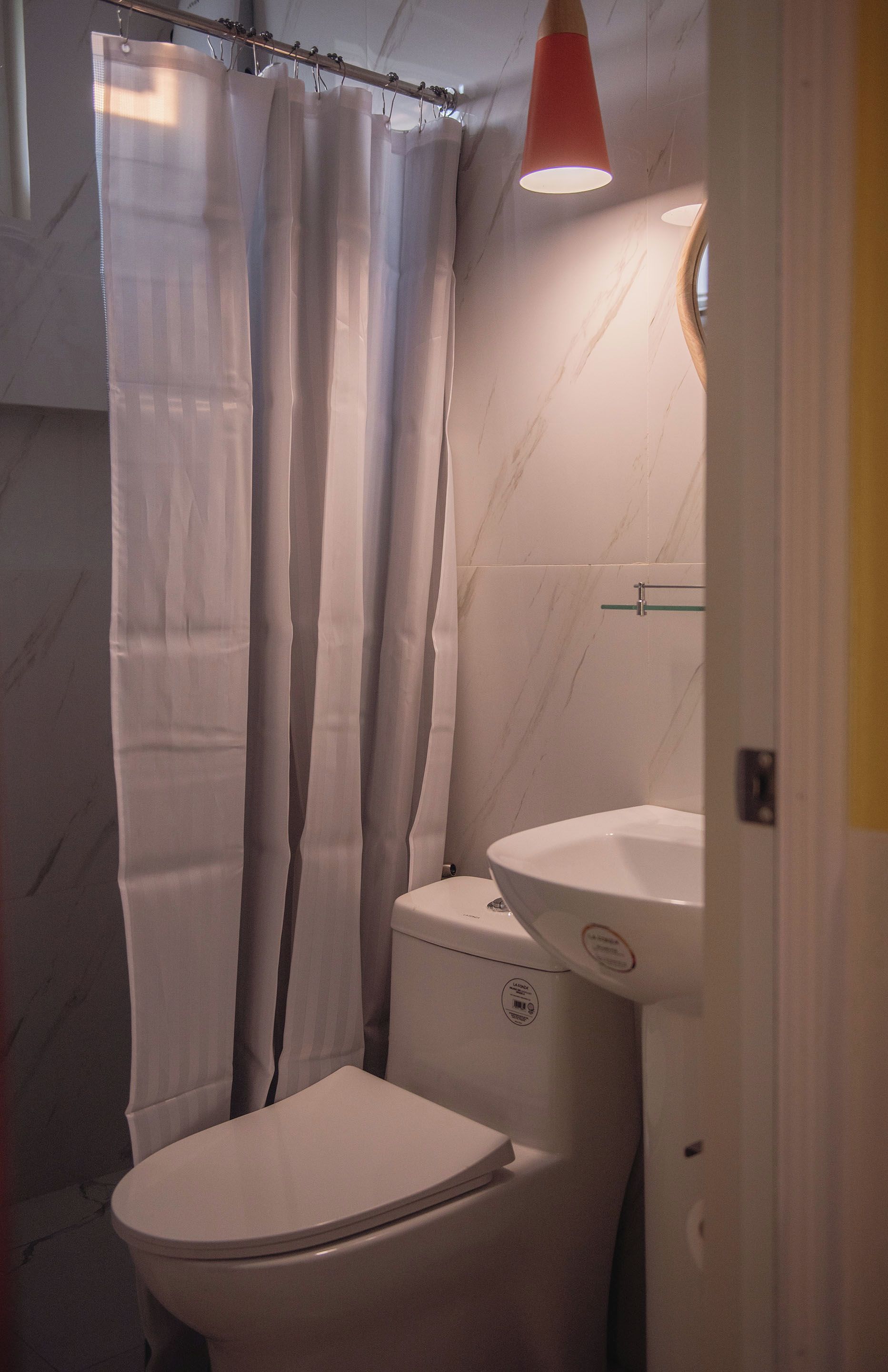 Un baño con inodoro, lavamanos y cortina de ducha.