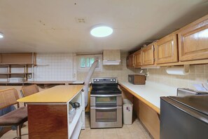 A kitchen with wooden cabinets, a built-in oven, a microwave, and a dining area with a bench and chairs. - Studio Guest Suite Outside Baltimore (Parkville)