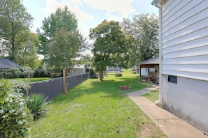 A residential backyard with a fenced area, a grassy lawn, and a house with a garage. - Studio Guest Suite Outside Baltimore (Parkville)