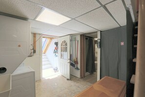 A room with a tiled floor, a door leading to another room, a window with a view, and a curtain on the door. - Studio Guest Suite Outside Baltimore (Parkville)