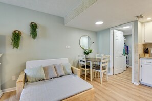 Ein Zimmer mit einem Bett, einem Esstisch mit Stühlen, einer Küchenzeile und einem Flur.