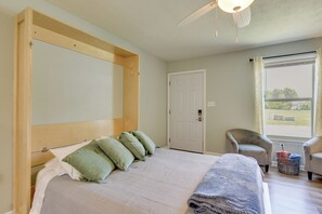 Quarto com uma cama grande, uma porta, uma janela e uma cadeira.