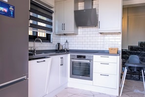 A modern kitchen with white cabinets, a built-in oven, and a black range hood. - Villa Savaya-2 Antalya (Kaş)