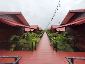 A corridor leading to multiple red-roofed structures, surrounded by lush greenery.