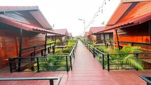 A corridor with wooden cabins, a central walkway, and greenery.