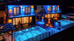 Um edifício de dois andares com piscina no terraço e área de estar ao ar livre.