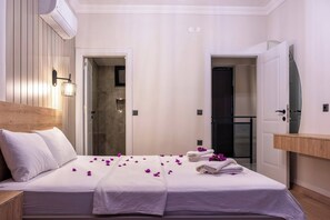 A hotel room with a bed, a wooden headboard, a wall-mounted air conditioner, a bathroom door, and a mirror. - Villa savaya 1 Antalya (Kaş)