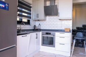 A modern kitchen with white cabinets, a built-in oven, and a black range hood. - Villa savaya 1 Antalya (Kaş)