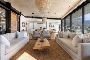 A modern living room with a large window, a wooden coffee table, and two sofas. - Ocean Villa - Iconinc Views, Perfect Location (Cape Town)