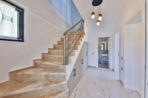 A staircase with marble steps and metal railings leading to a bathroom with a sink and mirror. - villa çınar-kaş Antalya (Kaş)