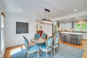 Cozinha moderna com ilha central, eletrodomésticos de aço inoxidável e área de jantar com mesa redonda e cadeiras.