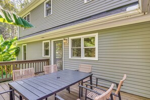 Eine Terrasse mit Tisch und Stühlen, eine überdachte Veranda und ein Haus mit grüner Außenfassade.