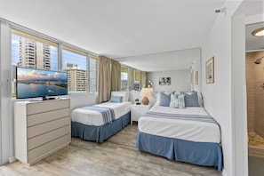 A hotel room with a bed, a desk, a TV, and a window with curtains. - Newly renovated Waikiki Studios (Honolulu)