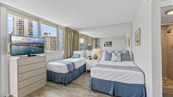 A hotel room with a bed, a desk, a TV, and a window with curtains.