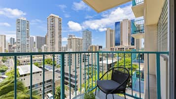 A balcony with a view of a cityscape, a chair, and a potted plant.