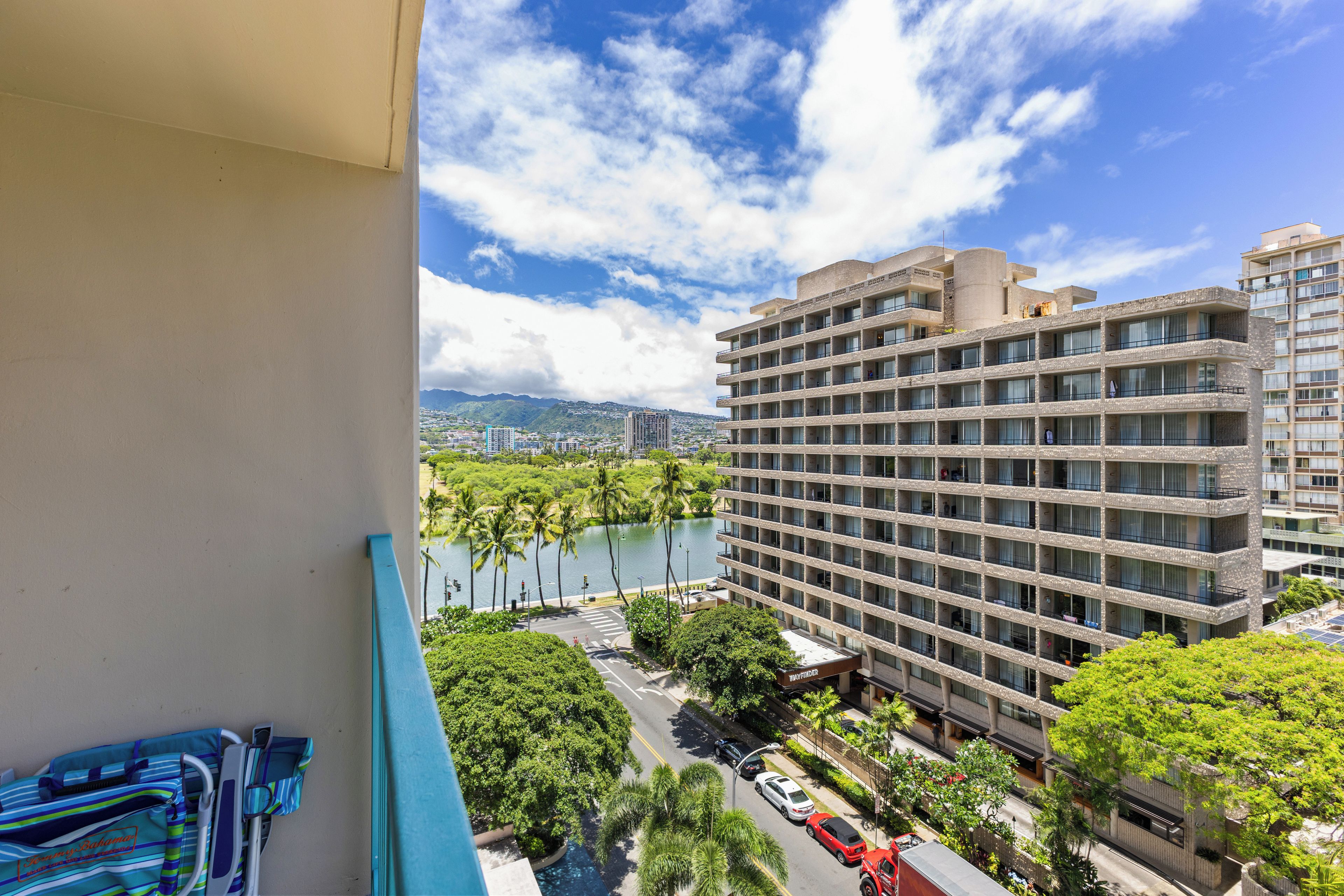 Hotel com vários andares, vista para um lago e para o horizonte urbano.