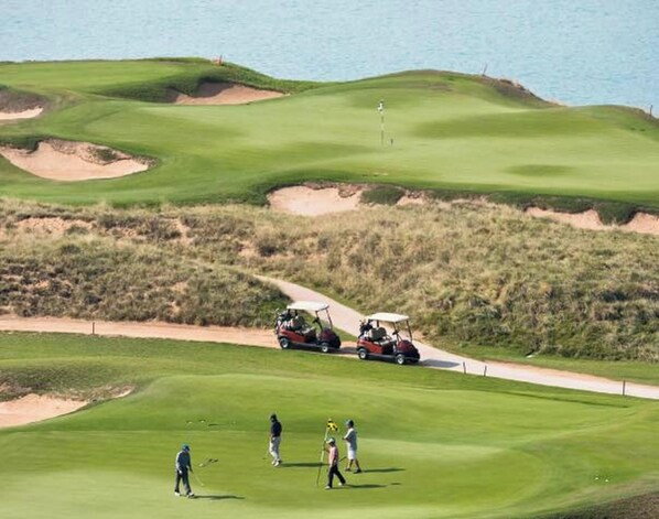 A golf course with bunkers, a water hazard, and a golf cart. - Sea View Luxury Stay with Panoramic Pool (Pattaya City)