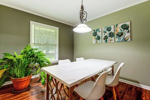 A dining area with a white table, chairs, a potted plant, and artwork on the wall. - Atlanta Home w/ Deck, 18 Mi Outside Dtwn (Atlanta)