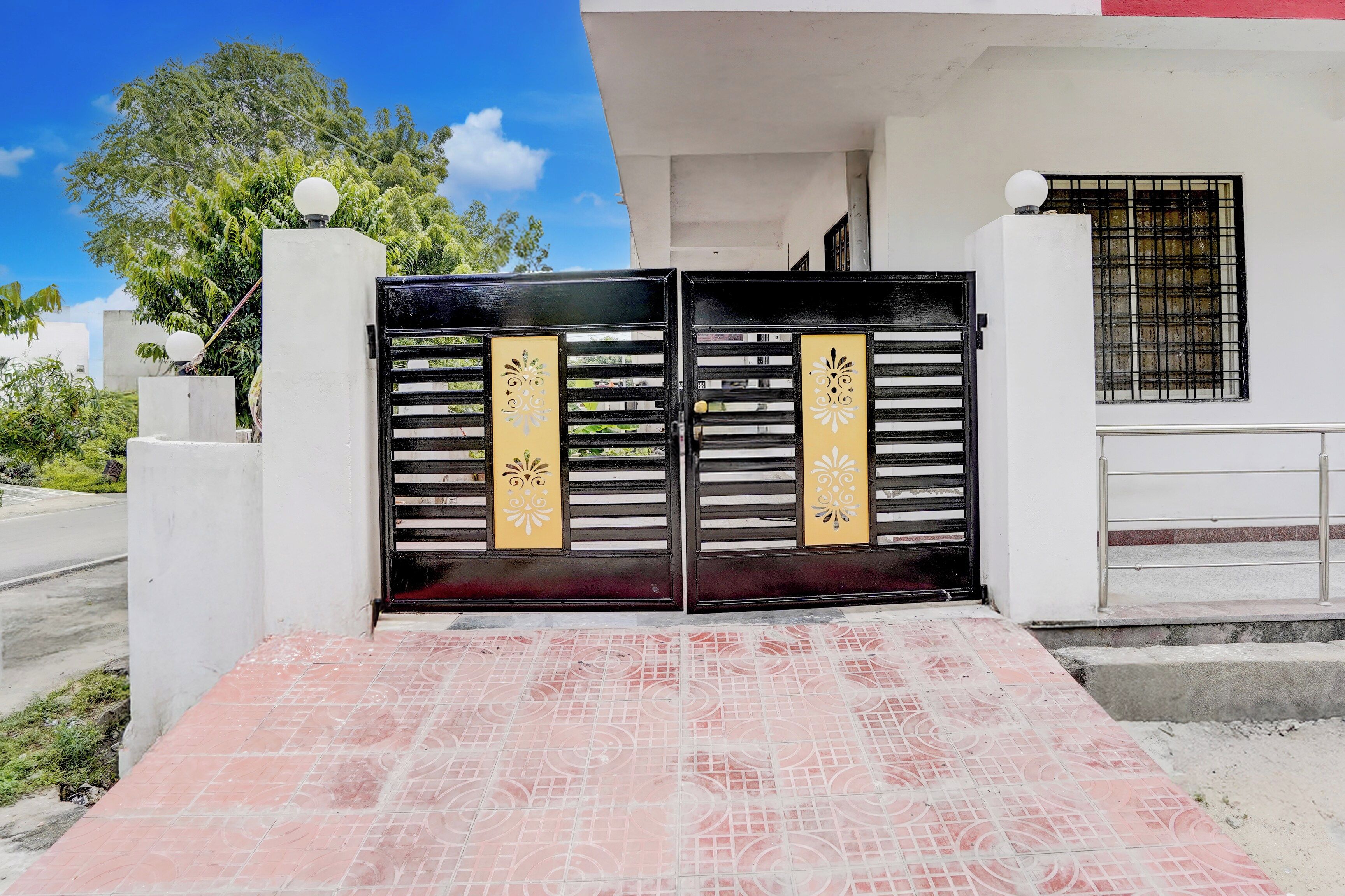 A gated entrance with a tiled pathway leading to a building.