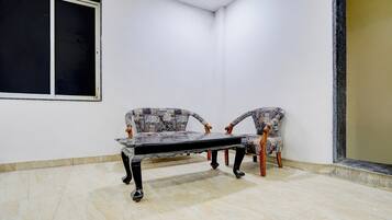 Una habitación con un ventanal grande, dos sillones estampados y una mesa.