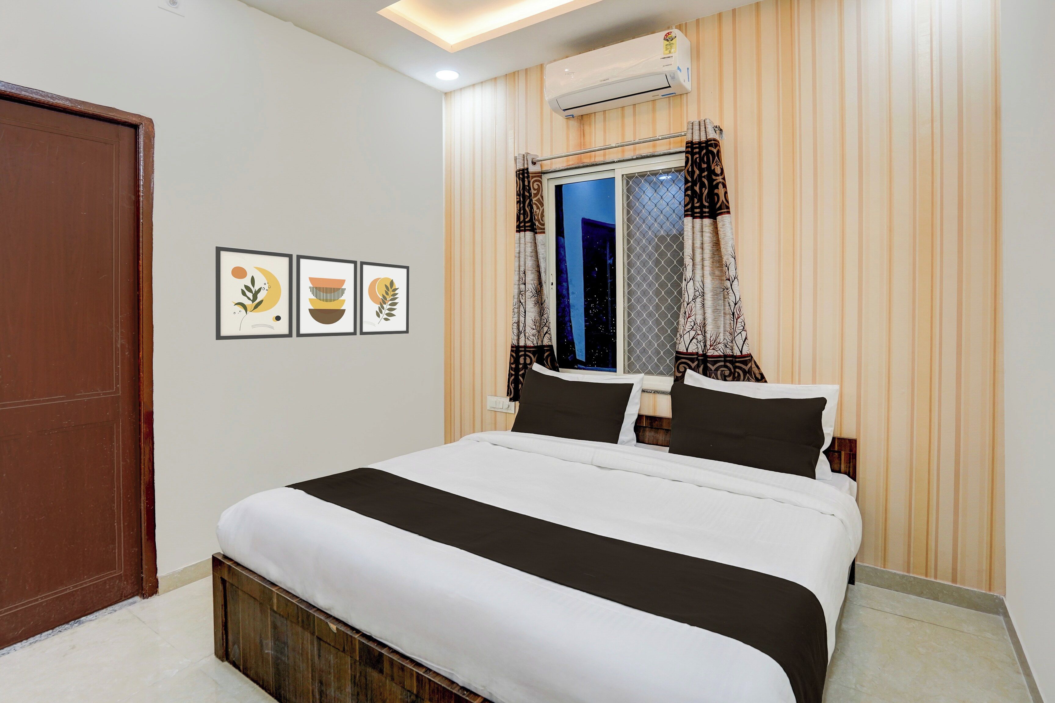 A bedroom with a bed, a window with curtains, and wall-mounted air conditioning.
