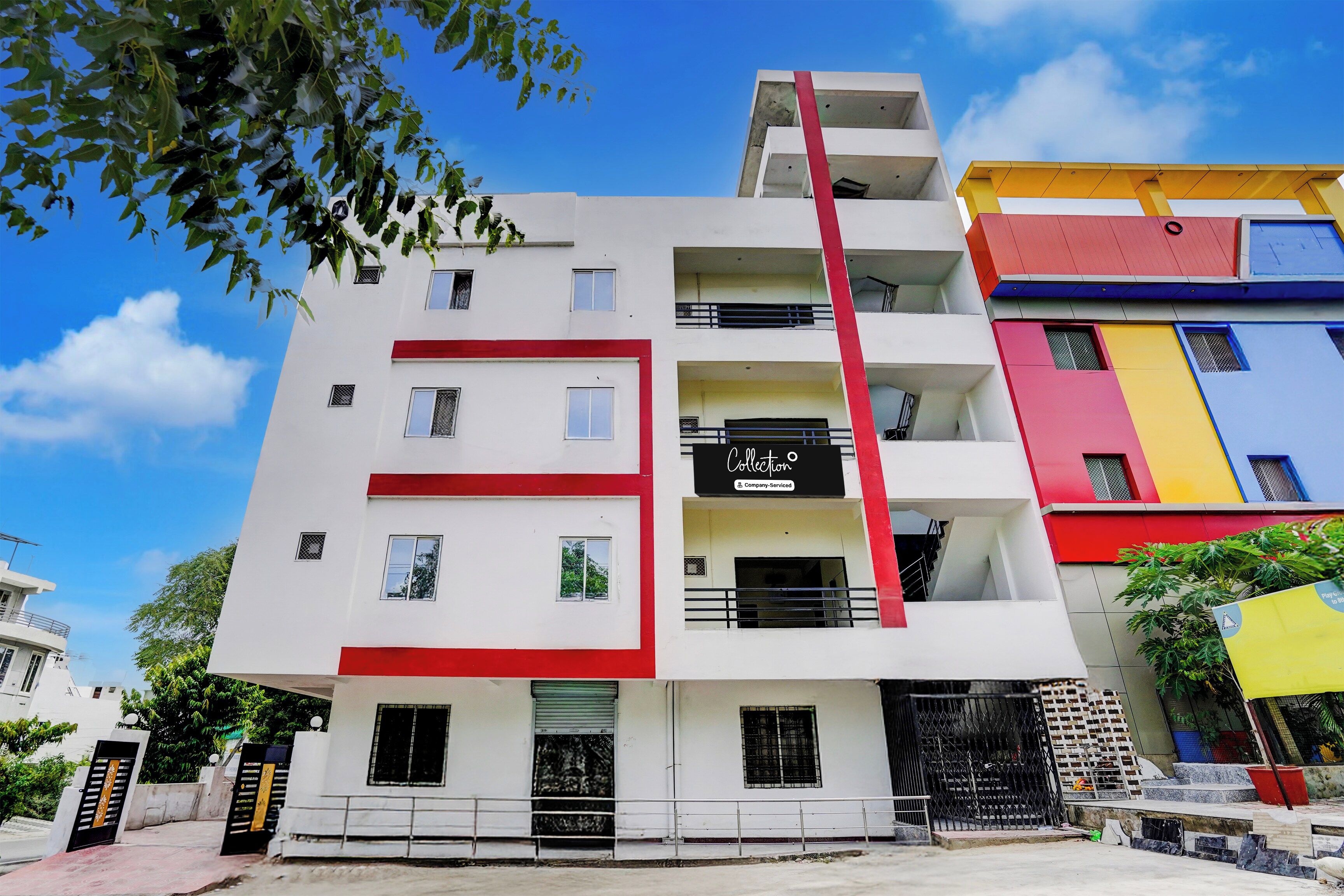 A multi-story building with a red and white facade, balconies, and a visible sign that reads 'Collection.'