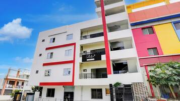 Un edificio de varios pisos con fachada roja y blanca, balcones y un letrero que indica un establecimiento de servicios empresariales.