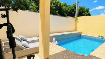 A gym with exercise equipment and a small pool with a tiled deck.