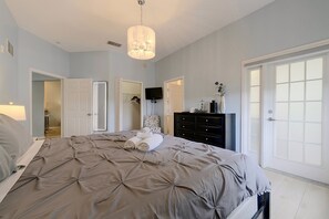 A bedroom with a large bed, a dresser, a television, and a door leading to another room. - Huge 4th Floor Resort Condo w/Bunk Rm near Disney (Kissimmee)