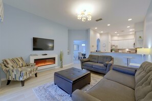 Un salon moderne doté d’un téléviseur à écran plat, d’une cheminée et de différents espaces pour s’asseoir.