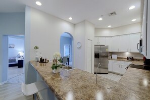 A modern kitchen with a granite countertop, stainless steel appliances, and white cabinetry. - Huge 4th Floor Resort Condo w/Bunk Rm near Disney (Kissimmee)