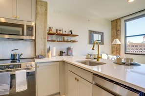 A modern kitchen with stainless steel appliances, a built-in dishwasher, and a large window offering a view of the cityscape. - 7th-Floor Condo: Walk to Cafes, Dining & More (Chattanooga)
