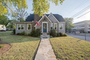 A two-story house with a stone facade, a front porch, and a flag. - Explore Scenic City | Cozy Getaway | Sleeps 8! (Chattanooga)