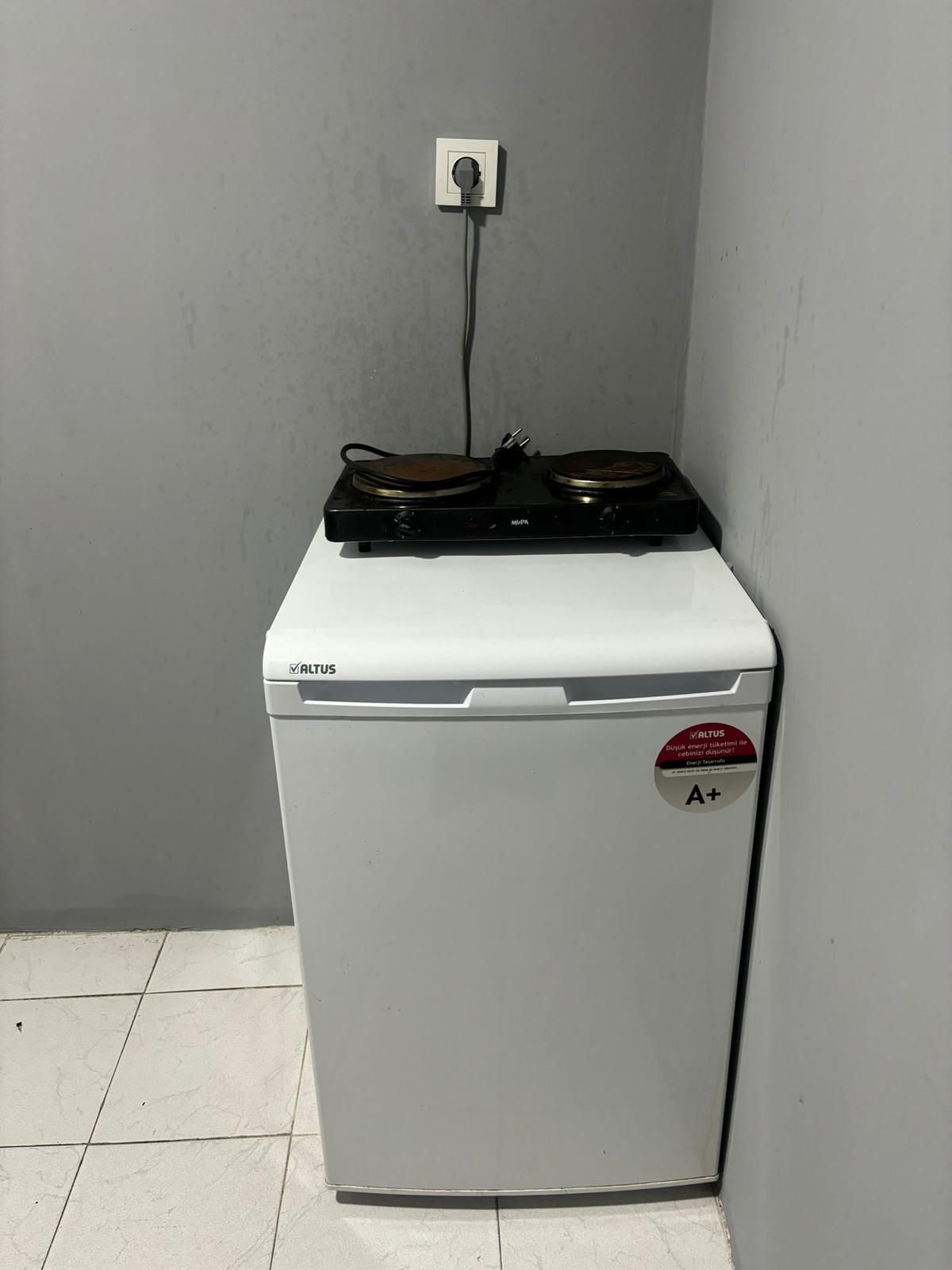Un appareil compact, de couleur blanche, doté d’un panneau de commande et d’une étiquette indiquant ses caractéristiques, apposée sur la porte.