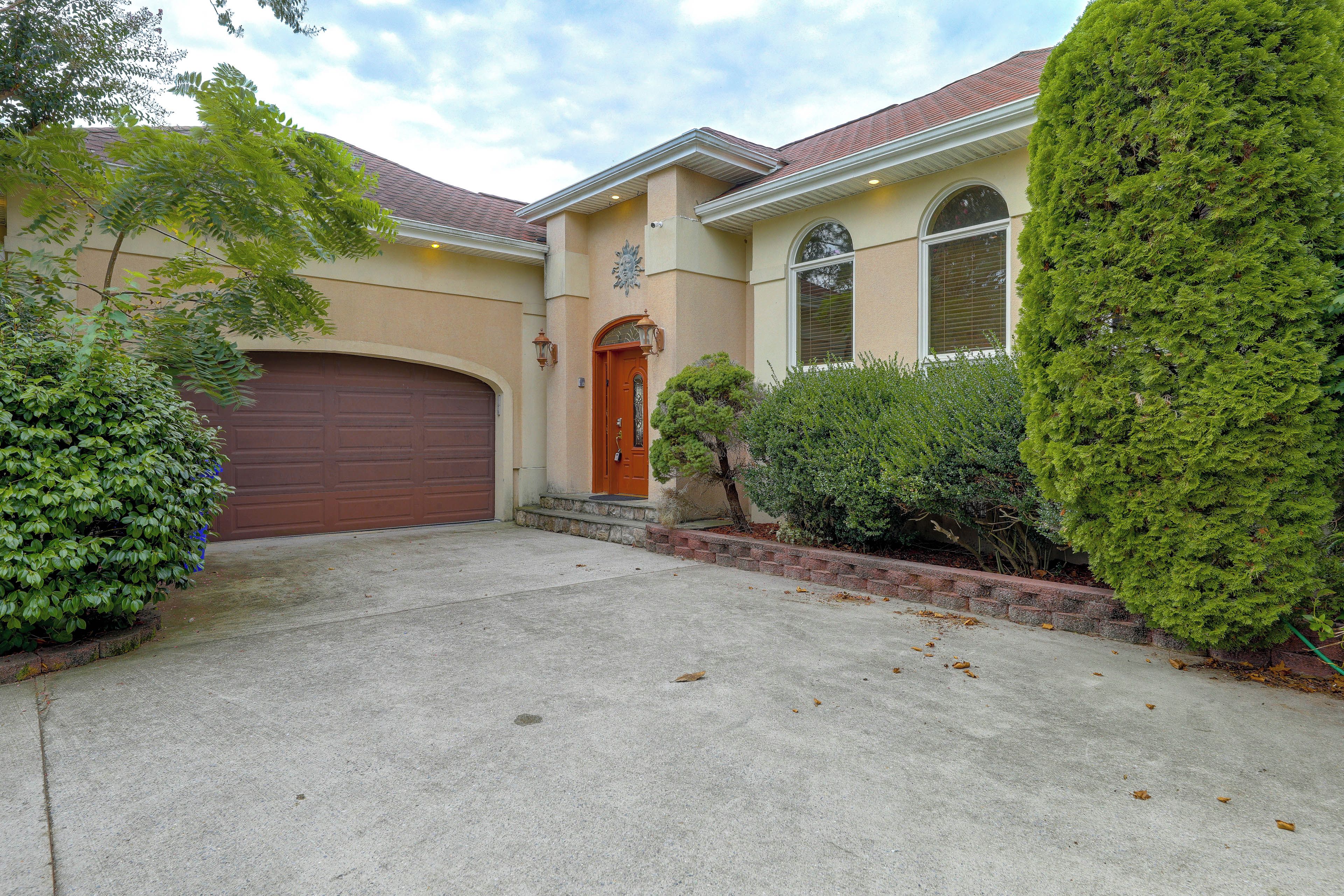 A residential house with a brown garage door, a front entrance with a door, and a well-maintained lawn.