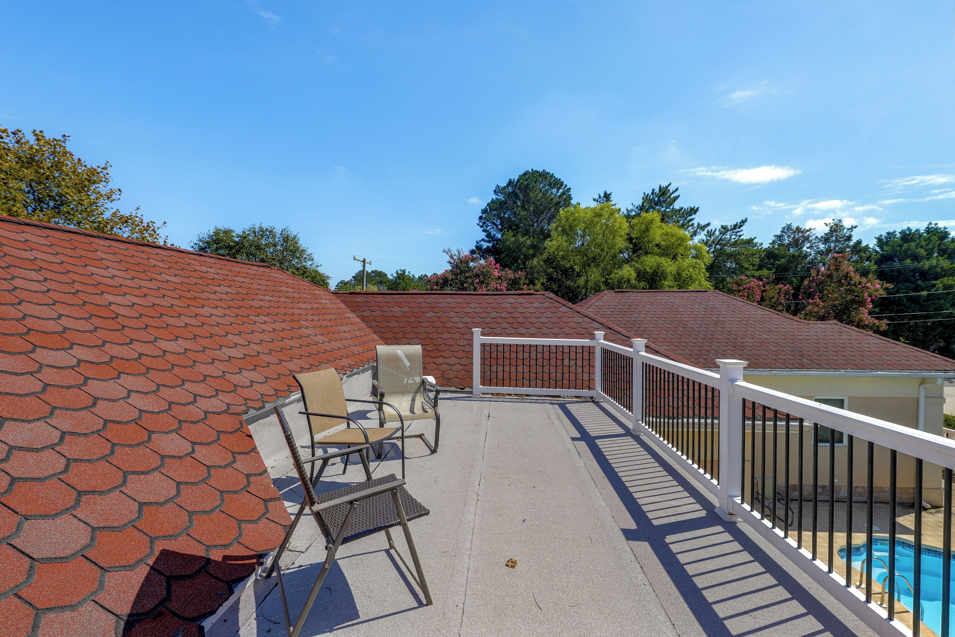 A rooftop patio with a pool, outdoor furniture, and a white railing.