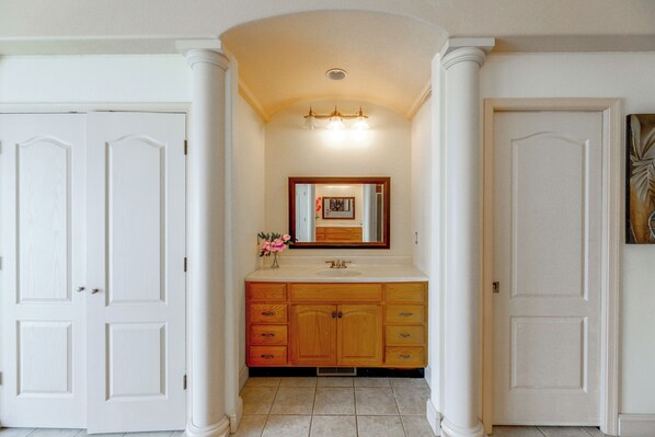 A bathroom with a vanity, a mirror, and two doors.