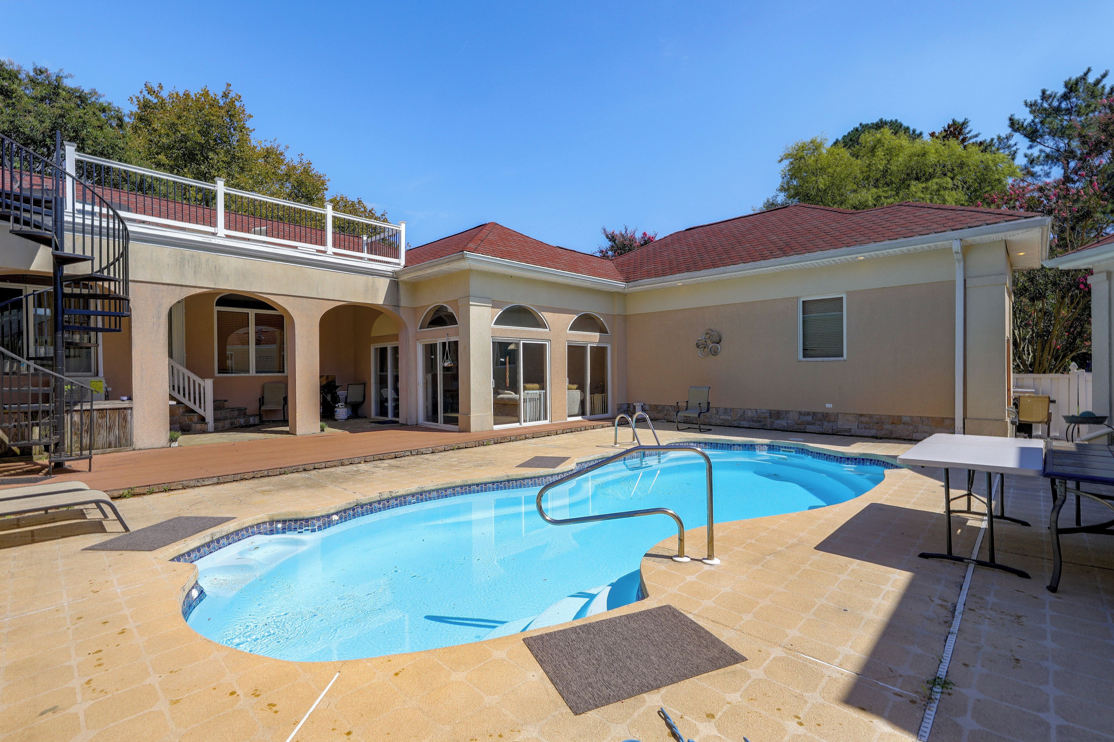 A residential property with a swimming pool, a covered patio, and a two-story house with a balcony.