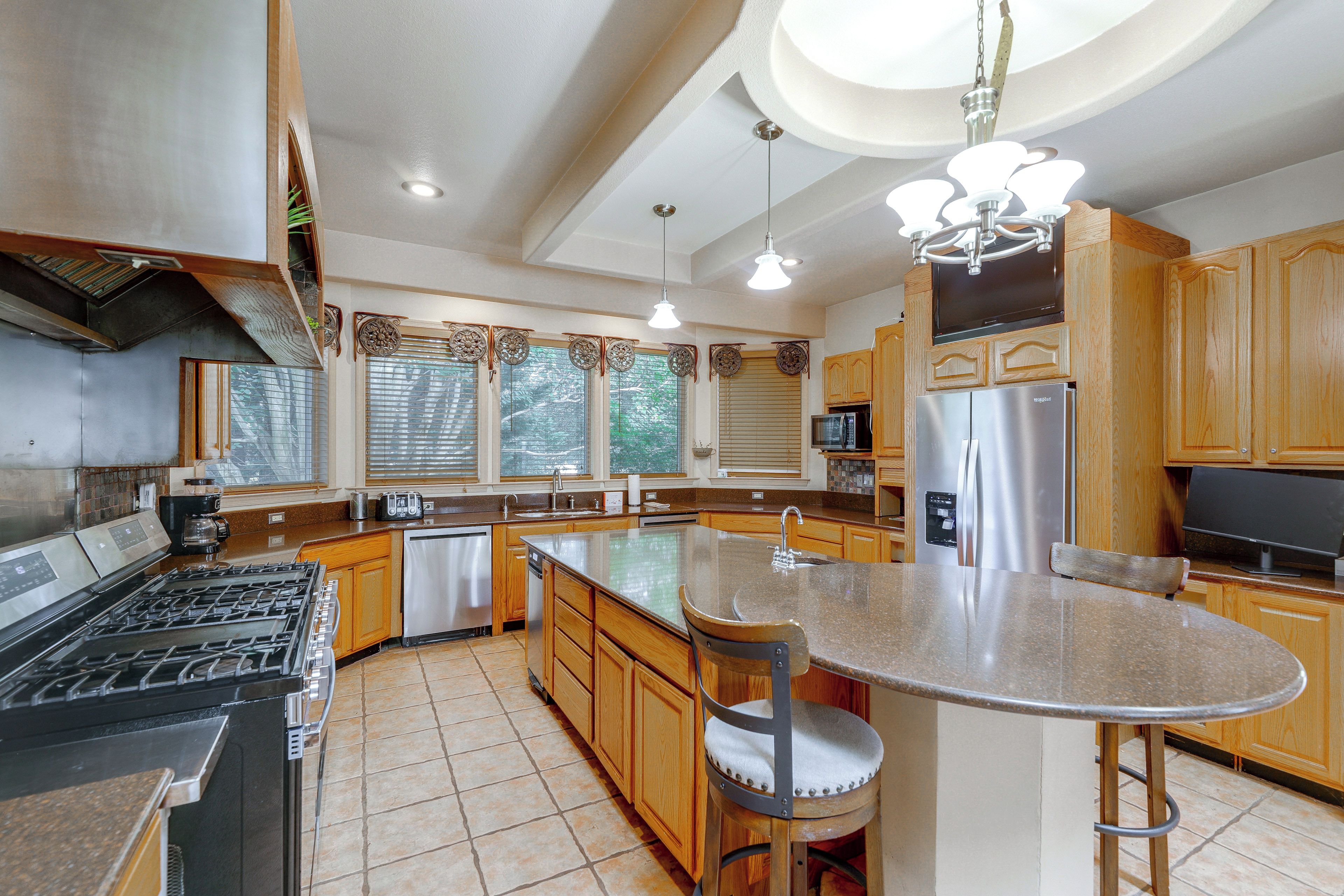 A modern kitchen with a central island, stainless steel appliances, and wooden cabinetry.