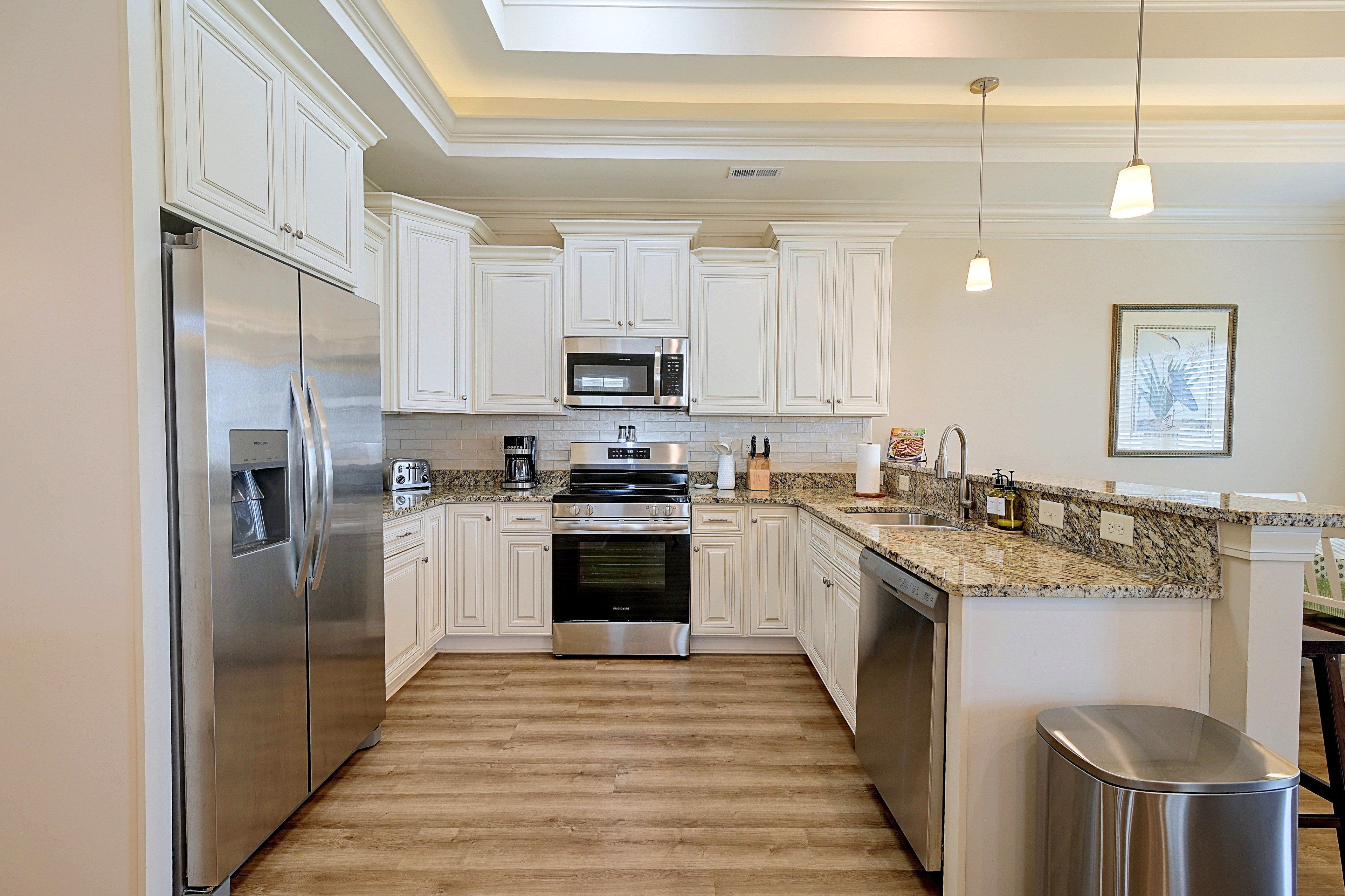 A modern kitchen with white cabinetry, stainless steel appliances, and a granite countertop.
