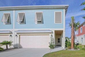 A two-story residential building with a garage, multiple windows with shutters, and a well-maintained lawn. - Stunning Murrells Inlet Townhome near MarshWalk (Murrells Inlet)