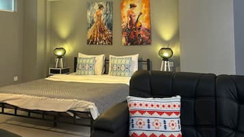 A modern bedroom with a bed, two wall-mounted lamps, and two paintings.