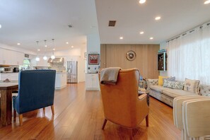 Uma sala moderna com um sofá, área de jantar com mesa e cozinha ao fundo.