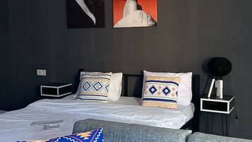Ein modernes Schlafzimmer mit einem Bett, einer Couch und zwei an der Wand befestigten Kunstwerken.